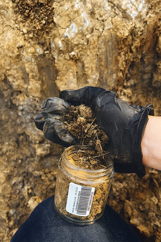 Close-up of gloved hand holding soil core sample during Phase II Environmental Site Assessment.