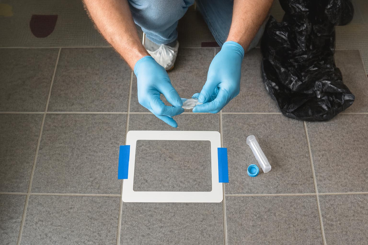 Certified lead inspector collecting a dust sample from floor tiles during a HUD-compliant lead-based paint risk assessment in a residential building.